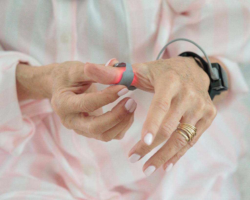 A patient wearing the Snap oximetry watch on the wrist with the ring sensor on the thumb